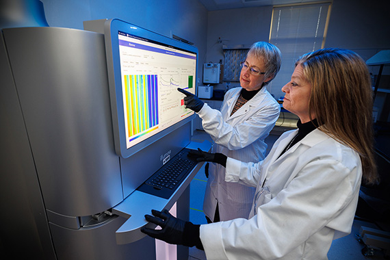 Two researchers review data on an Illumina NovaSeq X Plus DNA sequencing instrument.